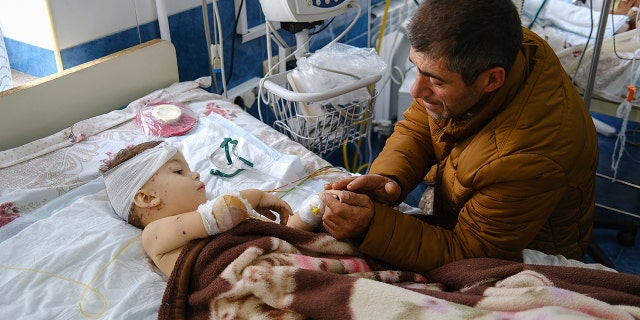 A man speaks with his child, wounded during shelling, in Stepanakert, the self-proclaimed Republic of Nagorno-Karabakh, Azerbaijan, Monday, Sept. 28, 2020. Fighting between Armenian and Azerbaijani forces over the disputed separatist region of Nagorno-Karabakh continued on Monday morning after erupting the day before, with both sides blaming each other for resuming the attacks. (Areg Balayan/PAN Photo via AP)