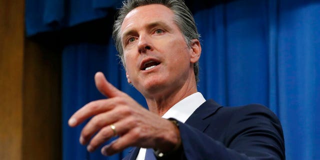 FILE: Gov. Gavin Newsom talks to reporters at his Capitol office in Sacramento, Calif. California will attempt to use its massive market power to increase the availability and lower the cost of prescription drugs.