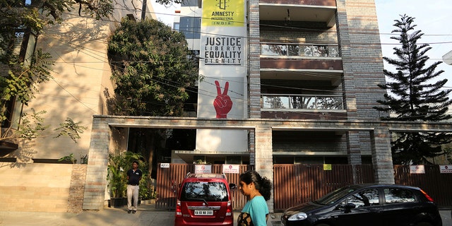 FILE - In this Tuesday, Feb. 5, 2019, file photo, a woman walks past the Amnesty International India headquarters in Bangalore, India. The Human rights watchdog said on Tuesday, Sept. 29, 2020, that it was halting its operation in India, citing reprisals from the government and the freezing of its bank accounts. Its announcement comes at a time amid growing concerns over the state of free speech in India where critics accuse Prime Minister Narendra Modi and his Hindu nationalist government of increasingly brandishing laws to silence human rights activists, intellectuals, filmmakers, students and journalists. (AP Photo/Aijaz Rahi, File)