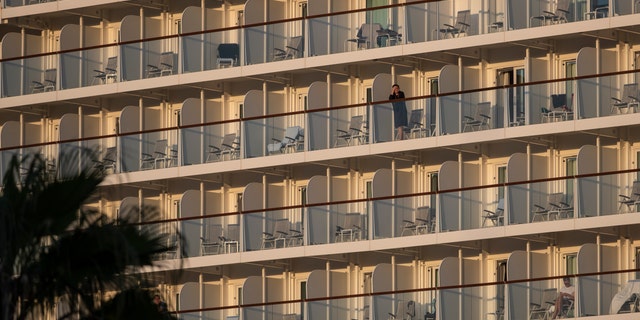 A passenger of the Mein Schiff 6 cruise ship stands outside her cabin as the ship is docked at Piraeus port, near Athens on Tuesday, Sept. 29. (AP Photo/Petros Giannakouris)