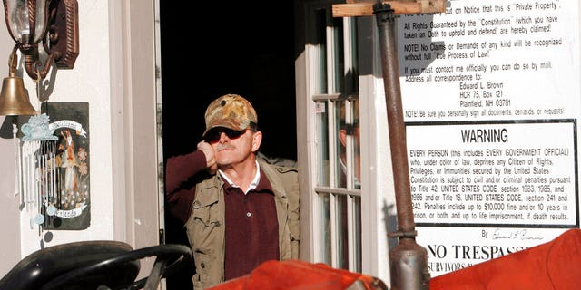 In this Jan. 17, 2007 photo, Edward Brown stands barricaded in the doorway of his home in Plainfield, N.H., saying he is prepared for an armed standoff. Brown was up for re-sentencing Tuesday Sept. 29, 2020 over a months long armed standoff with U.S. marshals in 2007 to protest a tax evasion conviction. (AP Photo/Jim Cole, File)