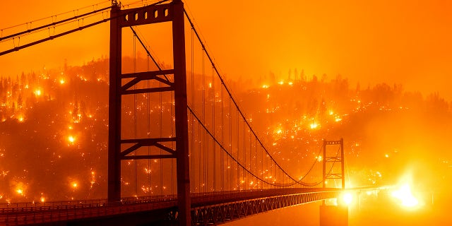 In this image taken with a slow shutter speed, embers light up a hillside behind the Bidwell Bar Bridge as the Bear Fire burns in Oroville, Calif., on Wednesday, Sept. 9, 2020.