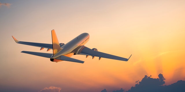 Passanger airplane flying above clouds in evening.