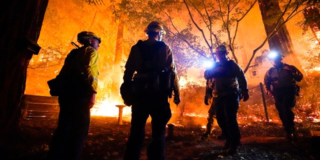 Firefighters make a stand in the backyard of a home in front of the advancing CZU August Lightning Complex Fire Friday, Aug. 21, 2020, in Boulder Creek, Calif.