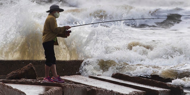 Waves crash as Houston resident Tinh Pham fishes from the rocks at Diamond Beach on the west end of the Galveston Seawall in Galveston, Texas on Saturday, Sept. 19, 2020.
