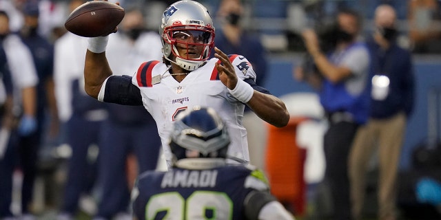 New England Patriots quarterback Cam Newton passes as Seattle Seahawks safety Ugo Amadi looks on during the second half of an NFL football game, Sunday, Sept. 20, 2020, in Seattle. (AP Photo/Elaine Thompson)