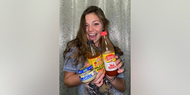 TikTok user Cammie Cooke poses with garlic, apple cider vinegar and hot sauce for her COVID food review. (Cammie Cooke)