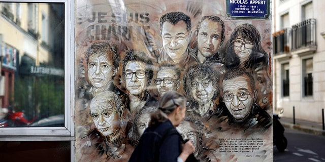 A woman walks past a painting by French street artist and painter Christian Guemy, known as C215, in tribute to members of Charlie Hebdo newspaper who were killed by jihadist gunmen in January 2015. (THOMAS COEX/AFP via Getty Images)