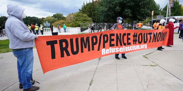 Protesters hold up a sign near the debate hall, Tuesday, Sept. 29, 2020, in Cleveland. The first presidential debate between Republican candidate President Donald Trump and Democratic candidate and former Vice President Joe Biden is being held in Cleveland Tuesday. (AP Photo/Tony Dejak)