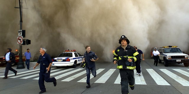 Policemen and firemen run away from the huge dust cloud caused as the World Trade Center's Tower One collapsed after terrorists crashed two hijacked planes into the twin towers on Sept. 11, 2001, in New York City. (Photo by Jose Jimenez/Primera Hora/Getty Images)