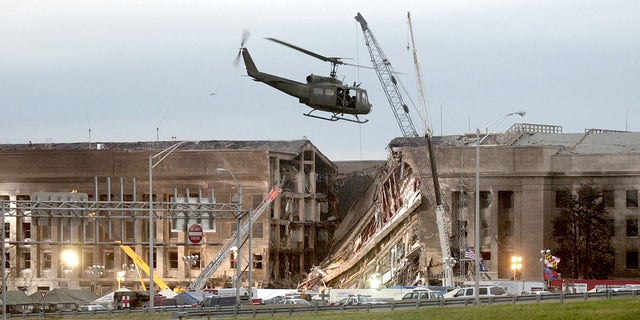 ARLINGTON, VA - SEPTEMBER 14, 2001: (SEPTEMBER 11 RETROSPECTIVE) A military helicopter flies in front of the Pentagon September 14, 2001 in Arlington, Virginia at the impact site where a hijacked airliner crashed into the building. (Photo by Stephen J. Boitano/Getty Images)