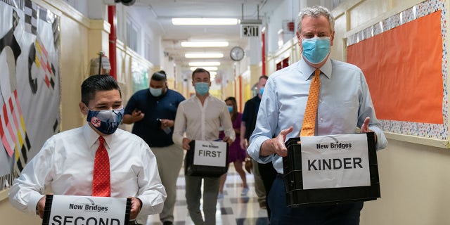 Richard Carranza, chancellor of the New York City Department of Education, left, and Bill de Blasio, mayor of New York, carry bins with supplies during a news conference at New Bridges Elementary School in the Brooklyn borough of New York, U.S., on Wednesday, Aug. 19, 2020. Photographer: Jeenah Moon/Bloomberg via Getty Images