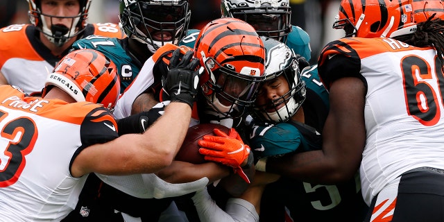 Cincinnati Bengals' Joe Mixon (28) is tackled by Philadelphia Eagles' Fletcher Cox (91) and T.J. Edwards (57) during the second half of an NFL football game, Sondag, Sept.. 27, 2020, in Philadelphia. (AP Photo/Laurence Kesterson)