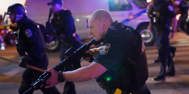 Police move after a Louisville Police officer was shot, Wednesday, Sept. 23, 2020, in Louisville, Ky. (AP Photo/John Minchillo)