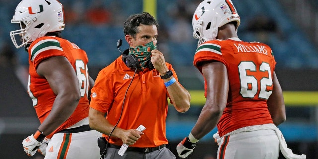 Miami coach Manny Diaz, center, walks on the field during an NCAA college football game against UAB in Miami Gardens, Fla., Thursday, Sept. 10, 2020. (Al Diaz/Miami Herald via AP)