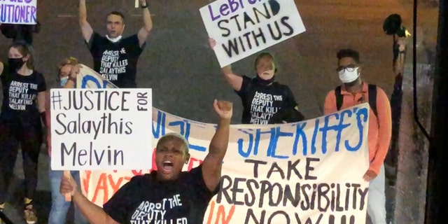 A small number of protesters of the August shooting in Central Florida of a Black man, Salaythis Melvin, hold signs and shout into megaphones, briefly blocking a bus chartered by the NBA from entering the Walt Disney World campus in Lake Buena Vista, Fla., Saturday night, Sept. 12, 2020, with the group saying it wanted LeBron James, Russell Westbrook and other top players to take notice. (AP Photo/Tim Reynolds)