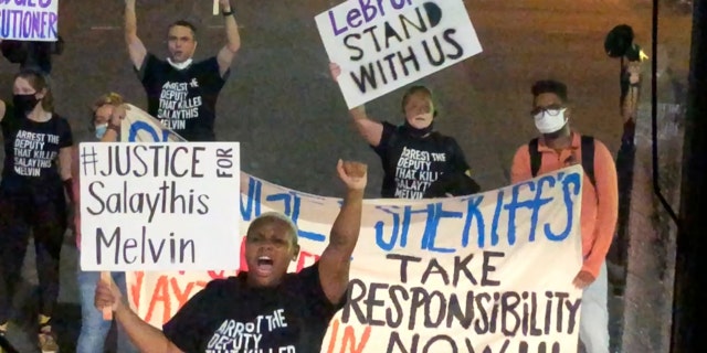 A small number of protesters of the August shooting in Central Florida of a Black man, Salaythis Melvin, hold signs and shout into megaphones, briefly blocking a bus chartered by the NBA from entering the Walt Disney World campus in Lake Buena Vista, Fla., Saturday night, Sept. 12, 2020, with the group saying it wanted LeBron James, Russell Westbrook and other top players to take notice. (AP Photo/Tim Reynolds)
