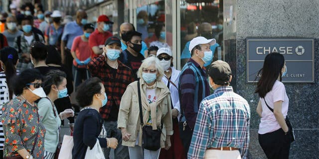 Patrons wearing protective masks wait to enter a Chase bank location, 星期一, 六月 8, 2020, in the Flushing section of the Queens borough of New York. After three bleak months, New York City will try to turn a page when it begins reopening Monday after getting hit first by the coronavirus, then an outpouring of rage over racism and police brutality. (AP Photo/Frank Franklin II)