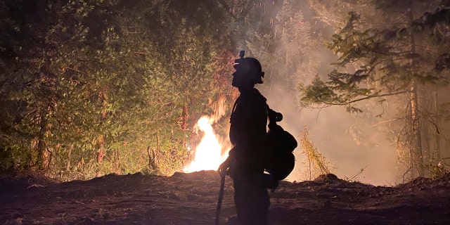 This photo provided by the Unified Fire Authority shows a Utah fire crew member on the scene working to protect the town of Butte Falls in southern Oregon.