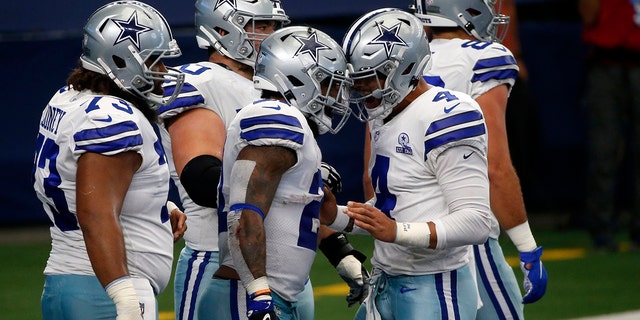 Dallas Cowboys' Joe Looney (73), Ezekiel Elliott, center, and Dak Prescott (4) celebrate a touchdown run by Elliott in the first half of an NFL football game against the Atlanta Falcons in Arlington, Texas, Sunday, Sept. 20, 2020. (AP Photo/Michael Ainsworth)