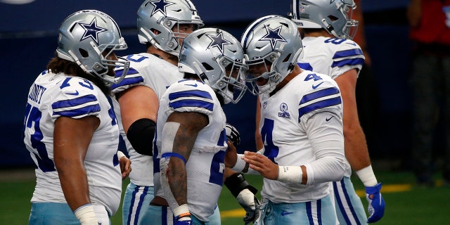 Dallas Cowboys' Joe Looney (73), Ezekiel Elliott, center, and Dak Prescott (4) celebrate a touchdown run by Elliott in the first half of an NFL football game against the Atlanta Falcons in Arlington, Texas, Sunday, Sept. 20, 2020. (AP Photo/Michael Ainsworth)