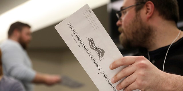 Election volunteer Tyler Jentoft-Johnson holds an absentee ballot as they're counted at the City Hall during the presidential primary election held amid the coronavirus disease (COVID-19) outbreak in Beloit, Wisconsin, U.S. April 7, 2020. REUTERS/Daniel Acker