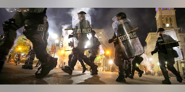 Police officers move past Louisville City Hall to clear protesters from a plaza after a grand jury considering the March killing of Breonna Taylor, a Black medical worker, in her home in Louisville, Kentucky, voted to indict one of three white police officers for wanton endangerment. REUTERS/Carlos Barria