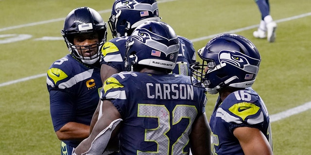 Seattle Seahawks running back Chris Carson (32) is greeted by quarterback Russell Wilson, left, after Carson caught a pass from Wilson for a touchdown against the New England Patriots during the second half of an NFL football game, Sunday, Sept. 20, 2020, in Seattle. (AP Photo/Elaine Thompson)