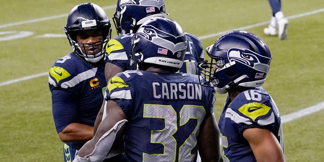 Seattle Seahawks running back Chris Carson (32) is greeted by quarterback Russell Wilson, left, after Carson caught a pass from Wilson for a touchdown against the New England Patriots during the second half of an NFL football game, Sunday, Sept. 20, 2020, in Seattle. (AP Photo/Elaine Thompson)
