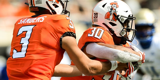 Oklahoma State quarterback Spencer Sanders (3) hands the ball off to running back Chuba Hubbard (30) during the first half of an NCAA college football game against Tulsa, Saturday, Sept. 19, 2020, in Stillwater, Okla. (AP Photo/Brody Schmidt)