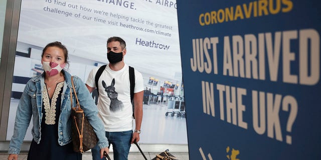 Passengers Charlotte and Frank, arrive at Heathrow Airport as they return from Mykonos in Greece, after the British Government added the island to the coronavirus quarantine list, at Heathrow, London, Tuesday Sept. 8, 2020. (Yui Mok/PA via AP)