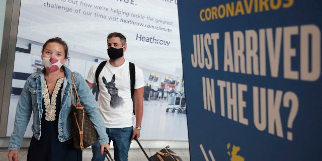 Passengers Charlotte and Frank, arrive at Heathrow Airport as they return from Mykonos in Greece, after the British Government added the island to the coronavirus quarantine list, at Heathrow, London, Tuesday Sept. 8, 2020. (Yui Mok/PA via AP)