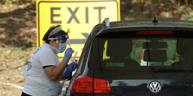 A person is tested for COVID-19 at a drive-through testing centre in a car park at Chessington World of Adventures, in Chessington, Greater London, Saturday, Sept. 19, 2020.