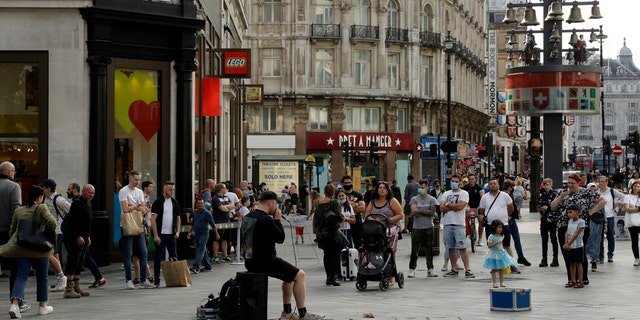 People listen to an entertainer perform in Leicester Square, central London, Saturday, Sept. 19, 2020.