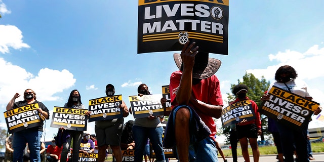 FILE - In this July 20, 2020, file photo, Eddie Perkins takes a knee during a protest rally outside Hartford Nursing & Rehabilitation Center in Detroit. Ahead of Labor Day, major U.S. labor unions say they are considering work stoppages in support of the Black Lives Matter movement. (AP Photo/Paul Sancya, File)