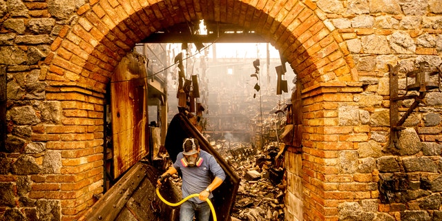 Cellar worker Jose Juan Perez extinguishes hotspots at Castello di Amorosa, Monday, Sept. 28, 2020, in Calistoga, Calif., which was damaged in the Glass Fire.