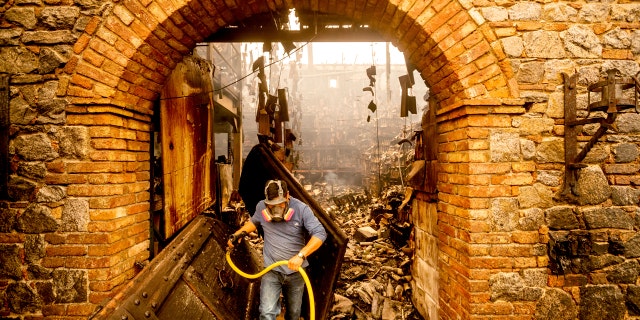 Cellar worker Jose Juan Perez extinguishes hotspots at Castello di Amorosa, Monday, Sept. 28, 2020, in Calistoga, Calif., which was damaged in the Glass Fire.