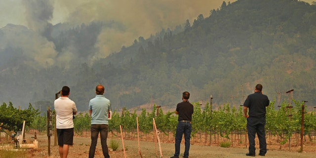 People gather to watch as the Glass Fire burns above in the hills of Calistoga, Calif., on Monday, Sept. 28, 2020.