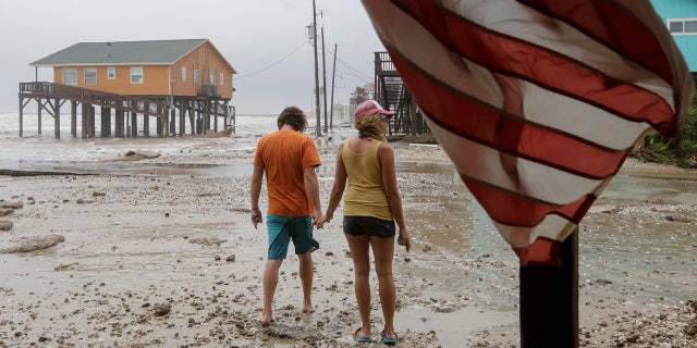 Adam Maubach, left, and Jo Dove look at the erosion caused by Tropical Storm Beta on Monday, Sept. 21, 2020, in Surfside, Texas.