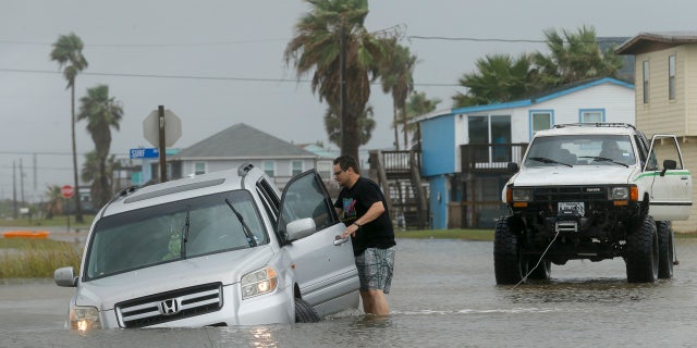 Jeff Williams gets back in his vehicle to try to get it out of the flooded road Monday, Sept. 21, 2020, in Surfside, Texas.