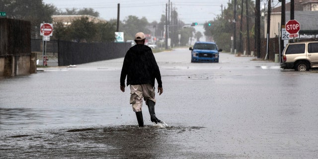 A man walks through a street flooded by Tropical Storm Beta Monday, Sept. 21, 2020, in Galveston, Texas.