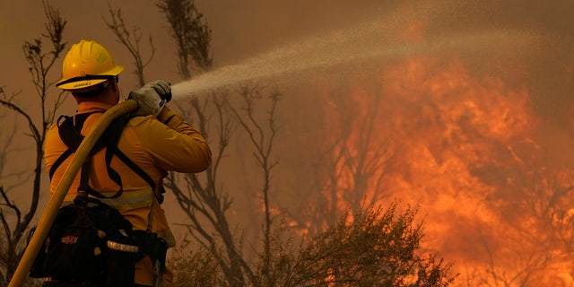 Jesse Vasquez, of the San Bernardino County Fire Department, hoses down hot spots from the Bobcat Fire on Saturday, Sept. 19, 2020, in Valyermo, Calif.