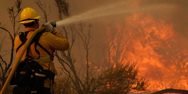 Jesse Vasquez, of the San Bernardino County Fire Department, hoses down hot spots from the Bobcat Fire on Saturday, Sept. 19, 2020, in Valyermo, Calif.