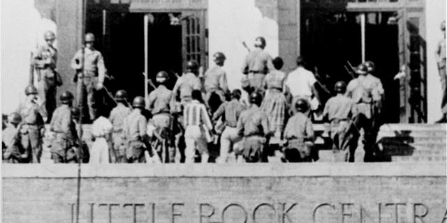 In this Sept. 25, 1957, file photo, troops of the 101st Airborne Division escort nine black students into Little Rock Central High School. (AP Photo, File)