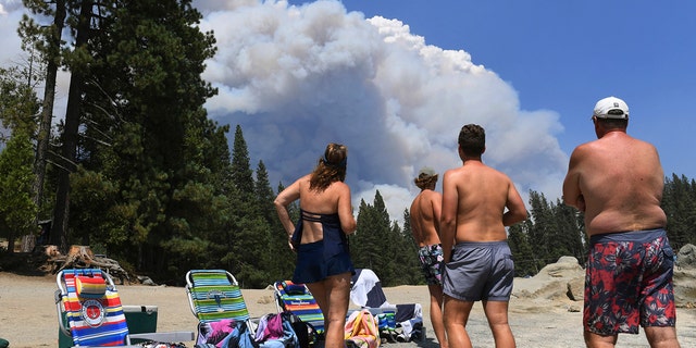 A family from Ventura County watches, from the shore of Shaver Lake, the billowing smoke from the Creek Fire, Saturday, Sept. 5, 2020, northeast of Fresno, Calif.