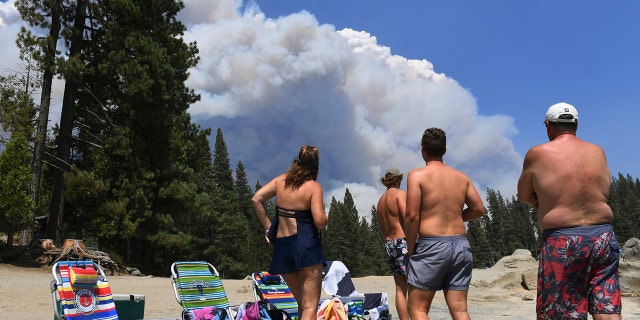 A family from Ventura County watches, from the shore of Shaver Lake, the billowing smoke from the Creek Fire, Saturday, Sept. 5, 2020, northeast of Fresno, Calif.