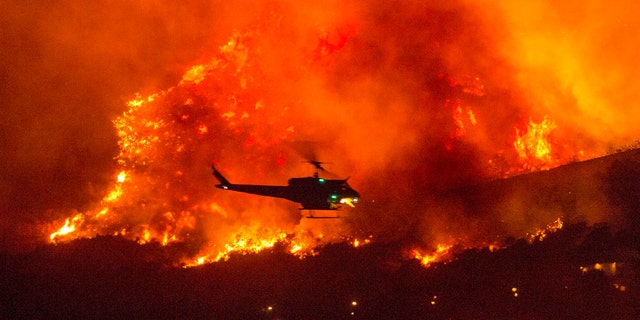 In this Saturday, Sept. 5, 2020, file photo, a helicopter prepares to drop water at a wildfire in Yucaipa, Calif.