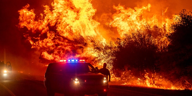 Flames lick above vehicles on Highway 162 as the Bear Fire burns in Oroville, Calif., on Wednesday, Sept. 9, 2020.