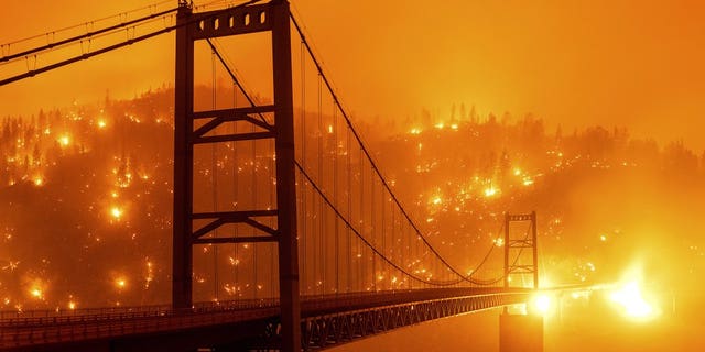 FILE - In this Sept. 9, 2020, file photo, taken with a slow shutter speed, embers light up a hillside behind the Bidwell Bar Bridge as the Bear Fire burns in Oroville, Calif. Two unusual weather phenomena combined to create some of the most destructive wildfires the West Coast states have seen in modern times. (AP Photo/Noah Berger, File)