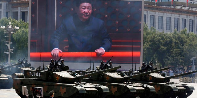 In this Thursday, Sept. 3, 2015 file photo, Chinese President Xi Jinping is displayed on a screen as Type 99A2 Chinese battle tanks take part in a parade commemorating the 70th anniversary of Japan's surrender during World War II held in front of Tiananmen Gate in Beijing. (AP Photo/Ng Han Guan, File)